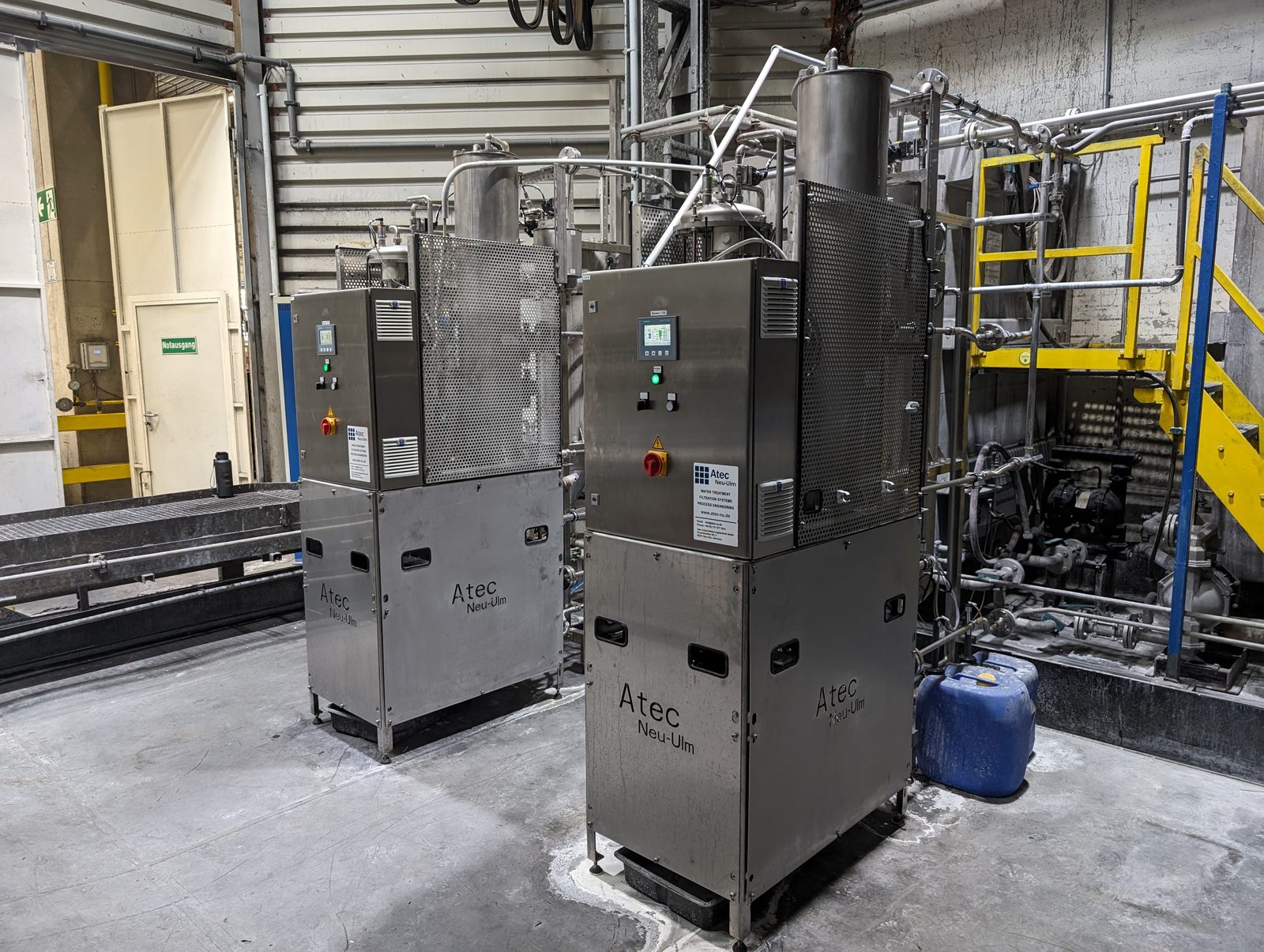 Zwei Atec Minitube Membranfiltrationsanlagen aus Edelstahl nebeneinander in einer Industriehalle, jeweils mit Bedienpanel und angeschlossener Verrohrung.